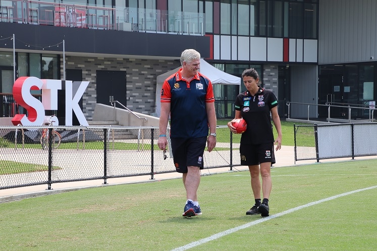 Gary Ayres (left) walks with Peta Searle (right) across a football field in St Kilda.