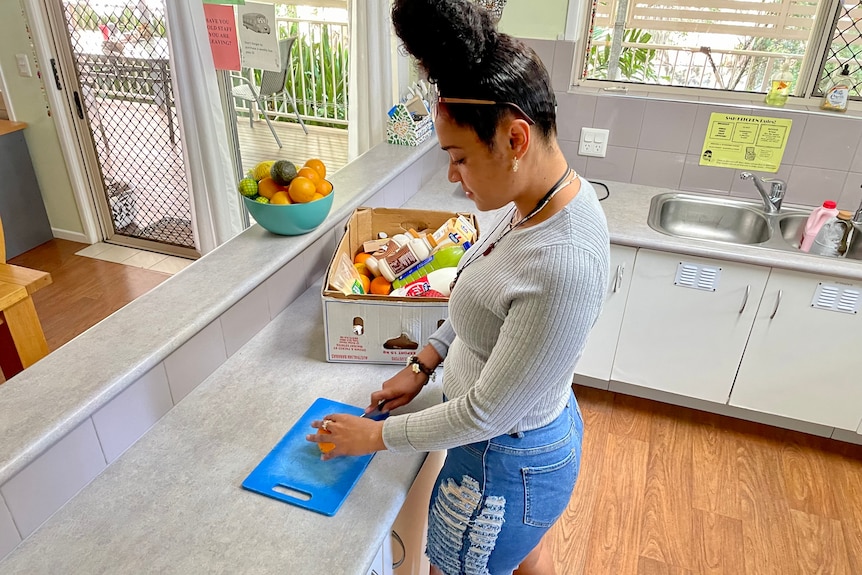 A woman cuts up an orange in a kitchen