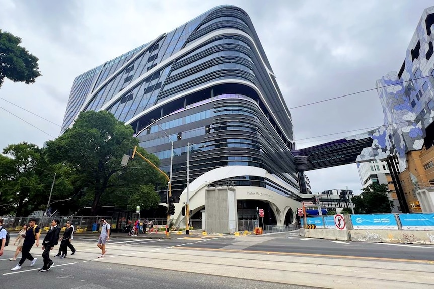 Pedestrians cross the road in front of the Peter MacCallum Cancer Centre