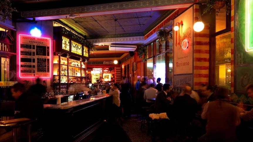 An interior of a bar with neon lighting around signage.