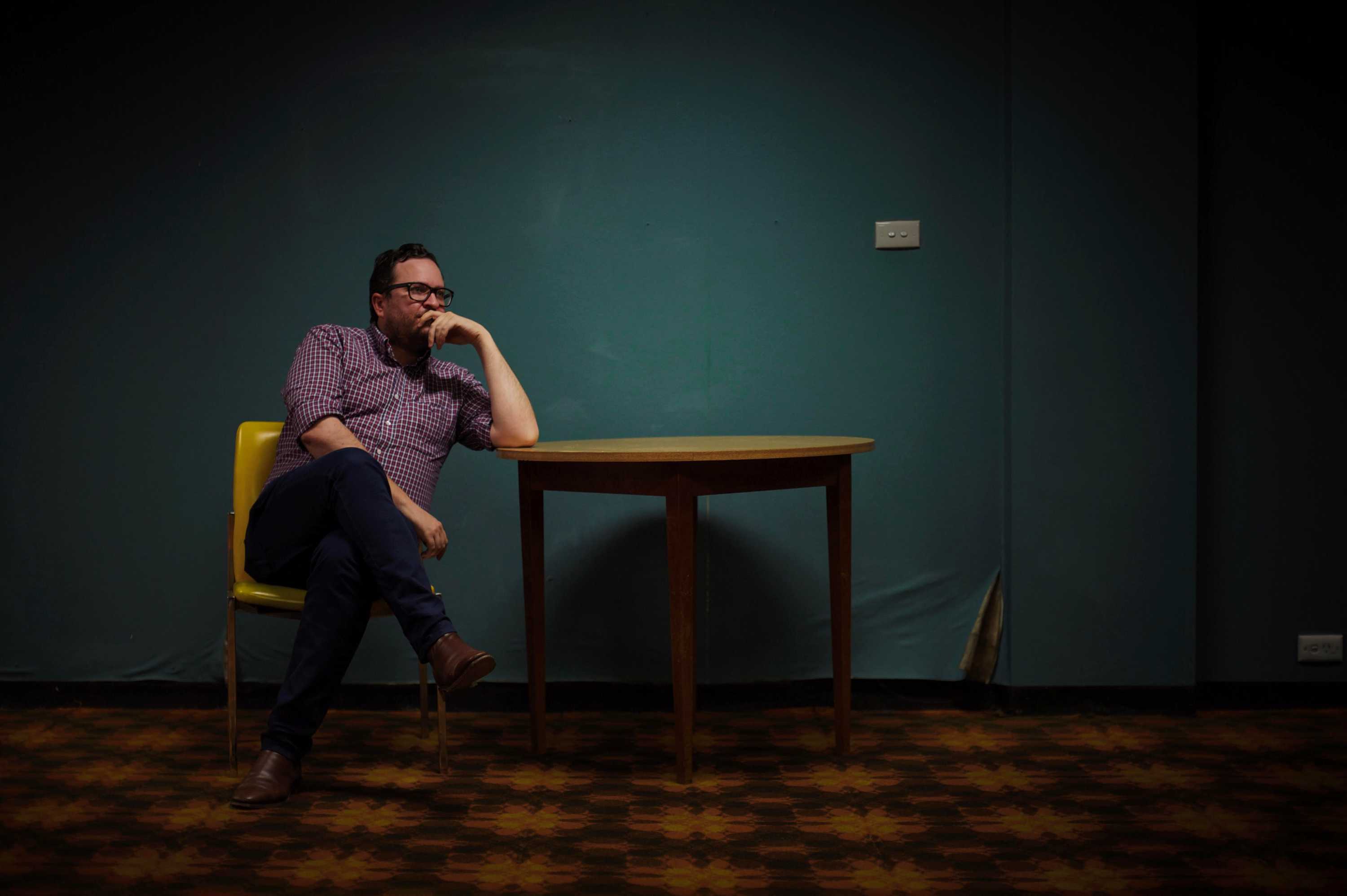 Author Rick Morton sits at a desk and stares thoughtfully into the distance