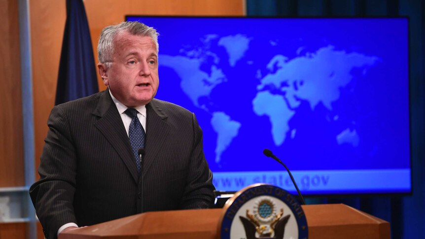 Acting Secretary of State John Sullivan stands behind a lectern