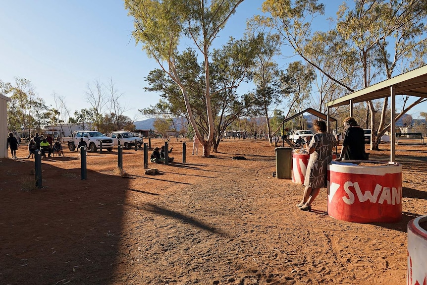 Leanne Liddle and Lance MacDonald lean against a bollard at a community meeting in Haasts Bluff.