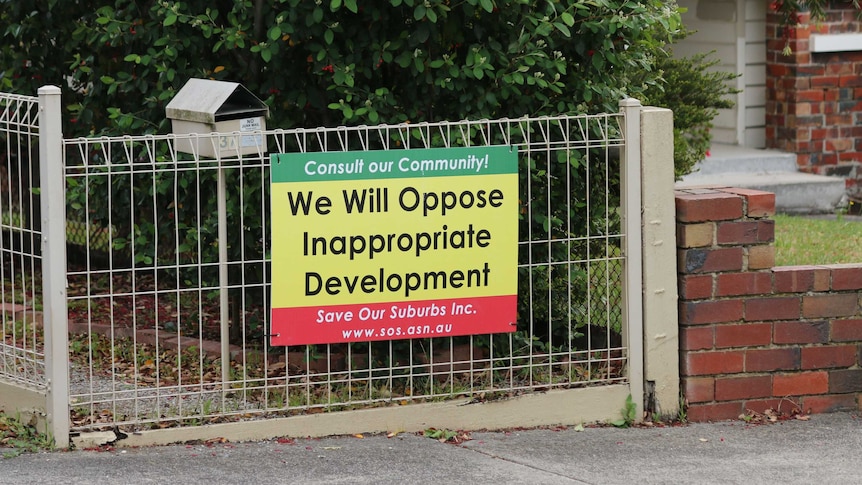A picture of a sign affixed to a fence reading: 'Consult our community. We will oppose inappropriate development'.