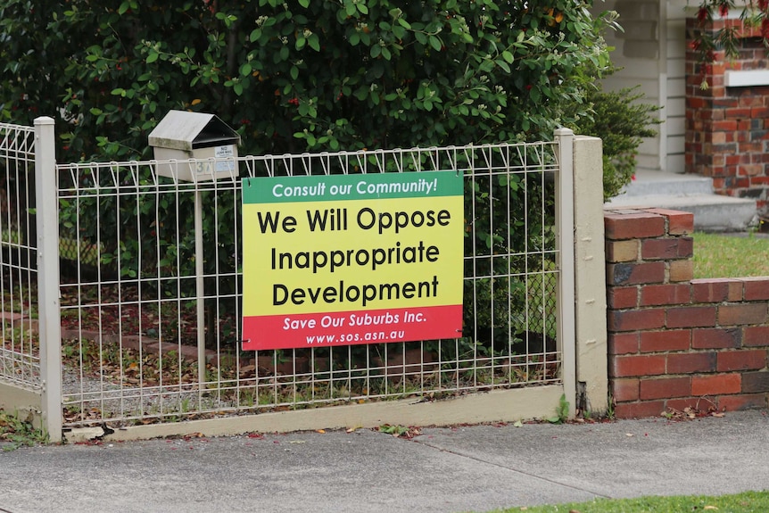 A picture of a sign affixed to a fence reading: 'Consult our community. We will oppose inappropriate development'.