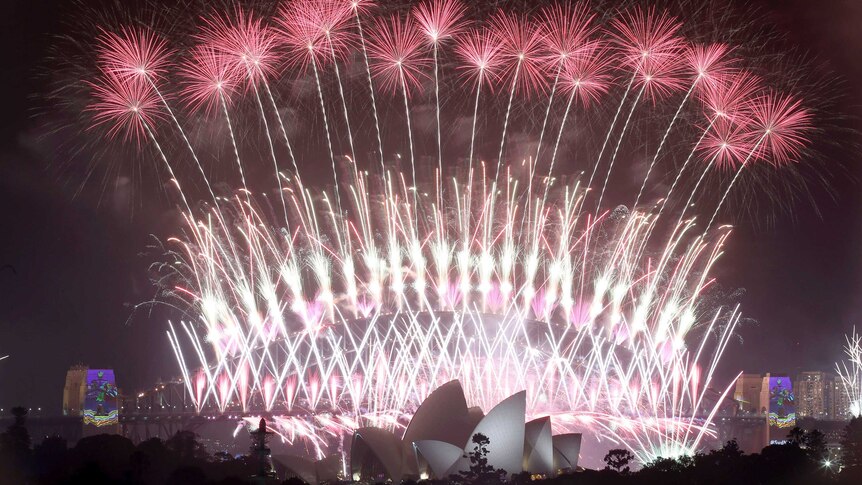 fireworks explode over the Sydney Opera House and Harbour Bridge