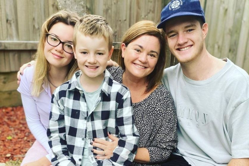 A woman sits surrounded by three teenage children for a story on bringing a premature baby home.