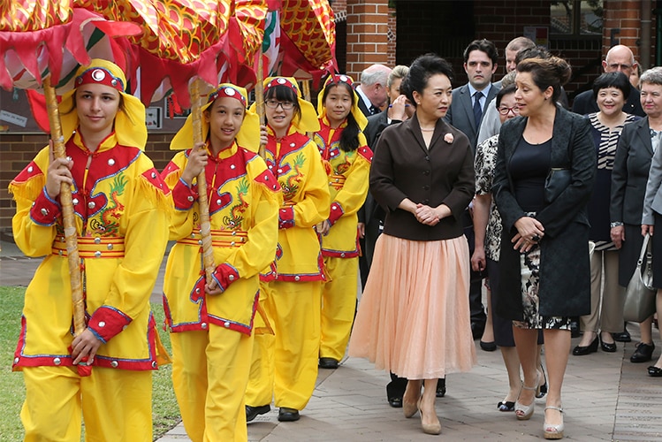 School girls dressed as a Chinese dragon walk alongside visiting women dignitaries.