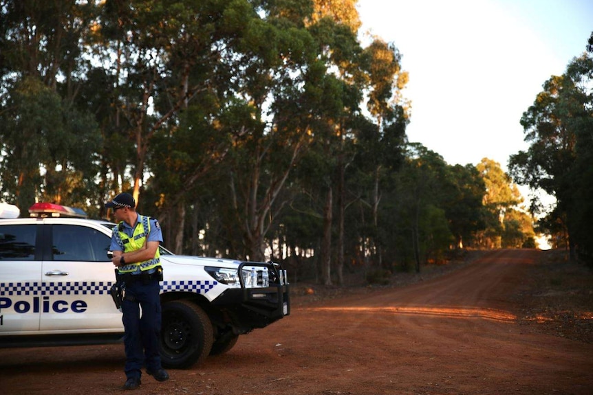 A police officer stands on an empty gravel road outside Margaret River.