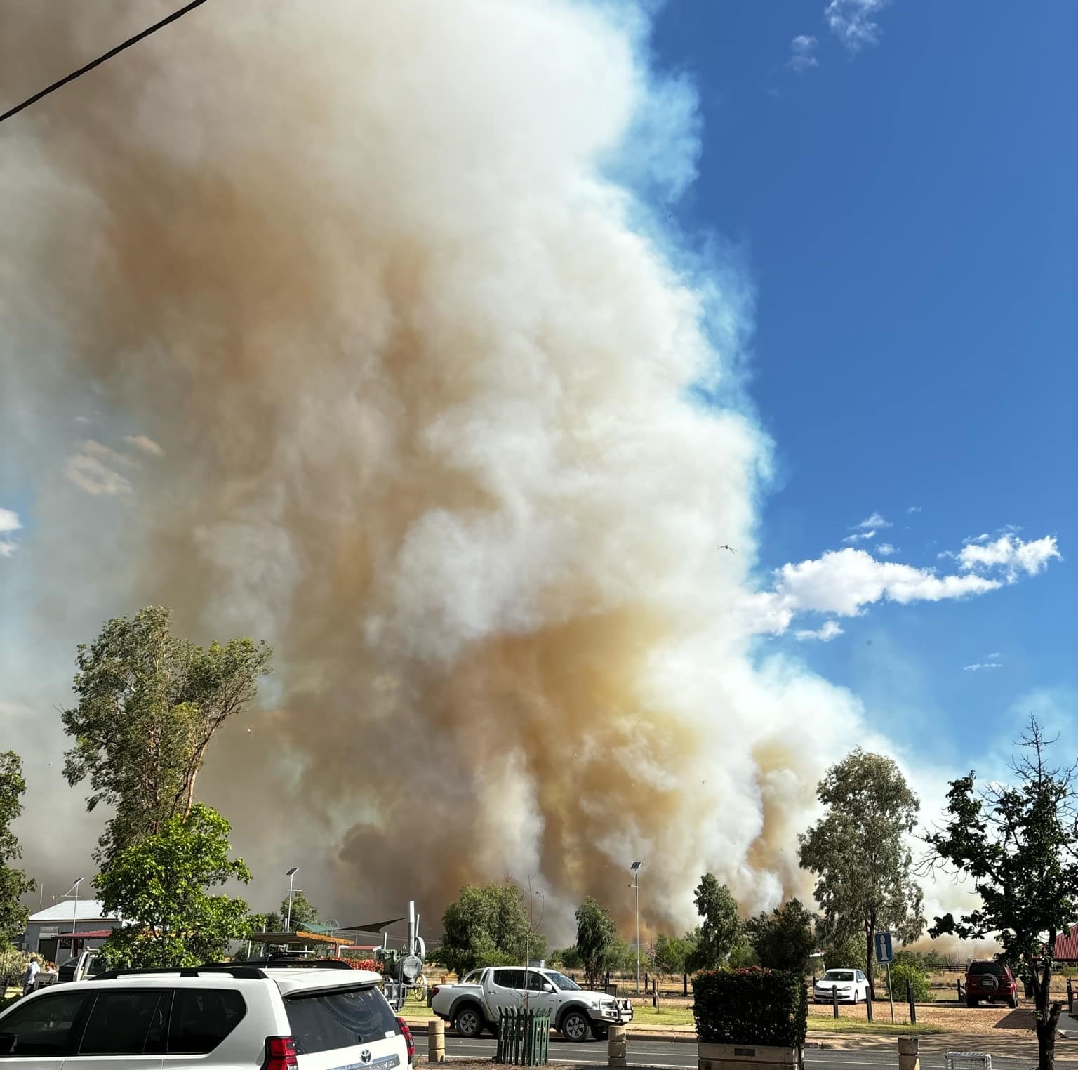 Plumes of bushfire smoke fill an otherwise blue sky in regional Queensland.