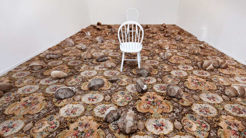 An art installation with carpet, rabbit skins and two white chairs