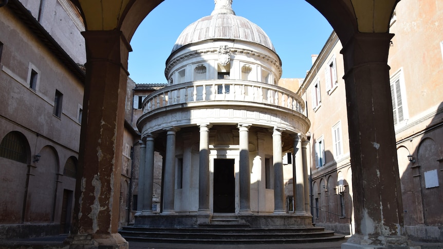 You view a small, circular neoclassical chapel complete with a dome, set within a renaissance-era courtyard.