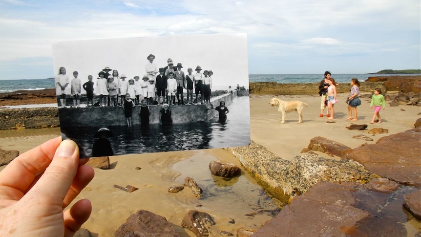 Old photo features people standing on edge of pool. Background features kids and dog standing in rock pools observing the pool.