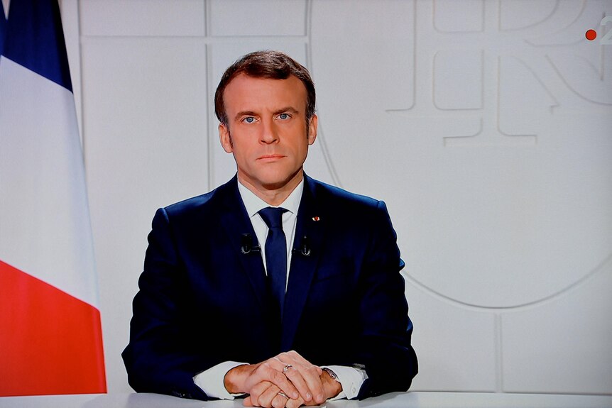 French President Emmanuel Macron seated.