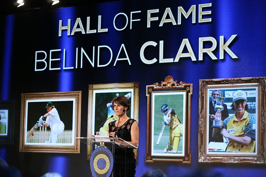 Former Australian cricketer Belinda Clark stands at a lectern behind a big sign saying 'Hall of Fame Belinda Clark'.