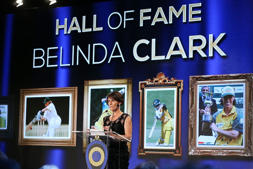 Former Australian cricketer Belinda Clark stands at a lectern behind a big sign saying 'Hall of Fame Belinda Clark'.