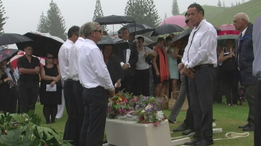 Mourners lay flowers on Colleen McCullough's coffin.