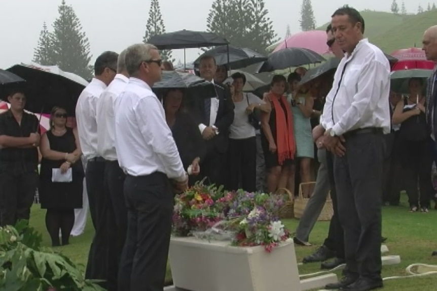 Mourners lay flowers on Colleen McCullough's coffin.
