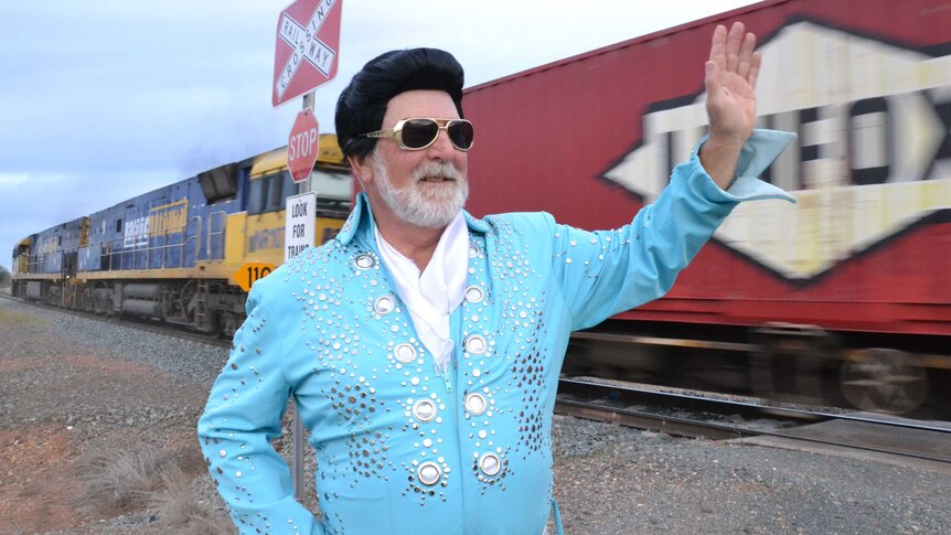 Ken Keith, dressed as Elvis, waves as a train passes
