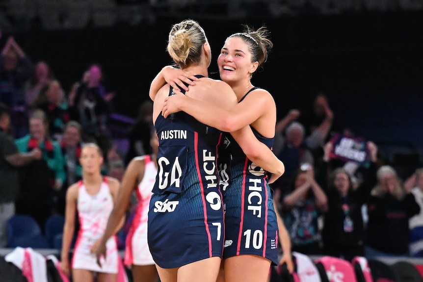 Two players hug wearing navy dresses as they smile