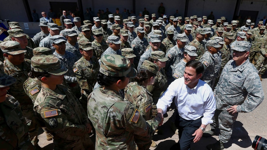 Arizona's Republican Govenor Doug Ducey shakes the hand of a troop in the middle of a crowd of Arizona National Guard soldiers
