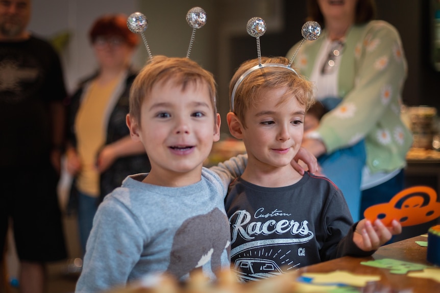 Two young boys with headbands on that have bug antlers attached to them