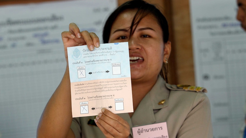 A Thai electoral worker holds up a ballot paper.