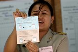 A Thai electoral worker holds up a ballot paper.