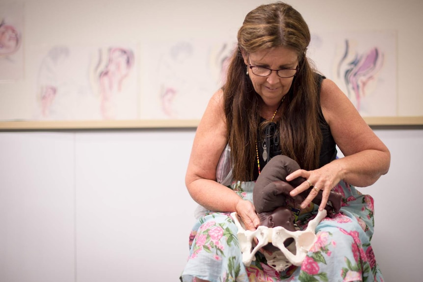Midwife and childbirth educator Annette Loadsman uses a model pelvis and baby to demonstrate how babies move through the pelvis.