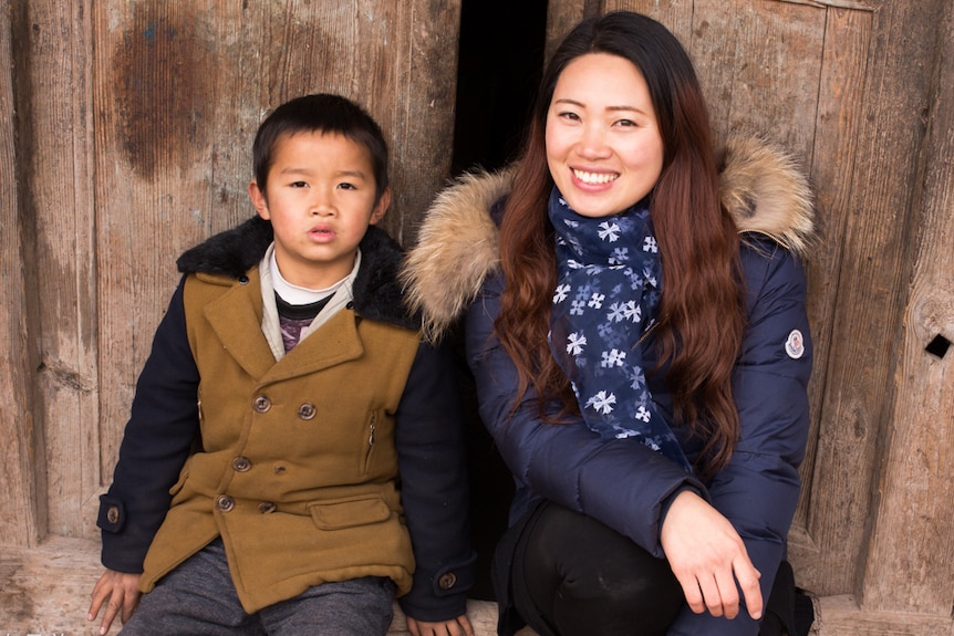 Tami Xiang and one of the left-behind children she photographed pose together for pictures
