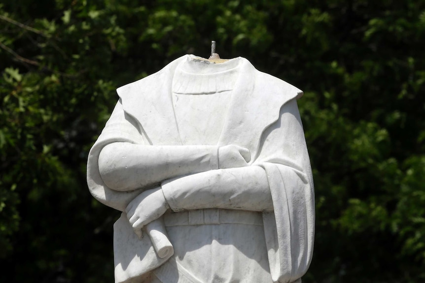 A damaged Christopher Columbus statue stands