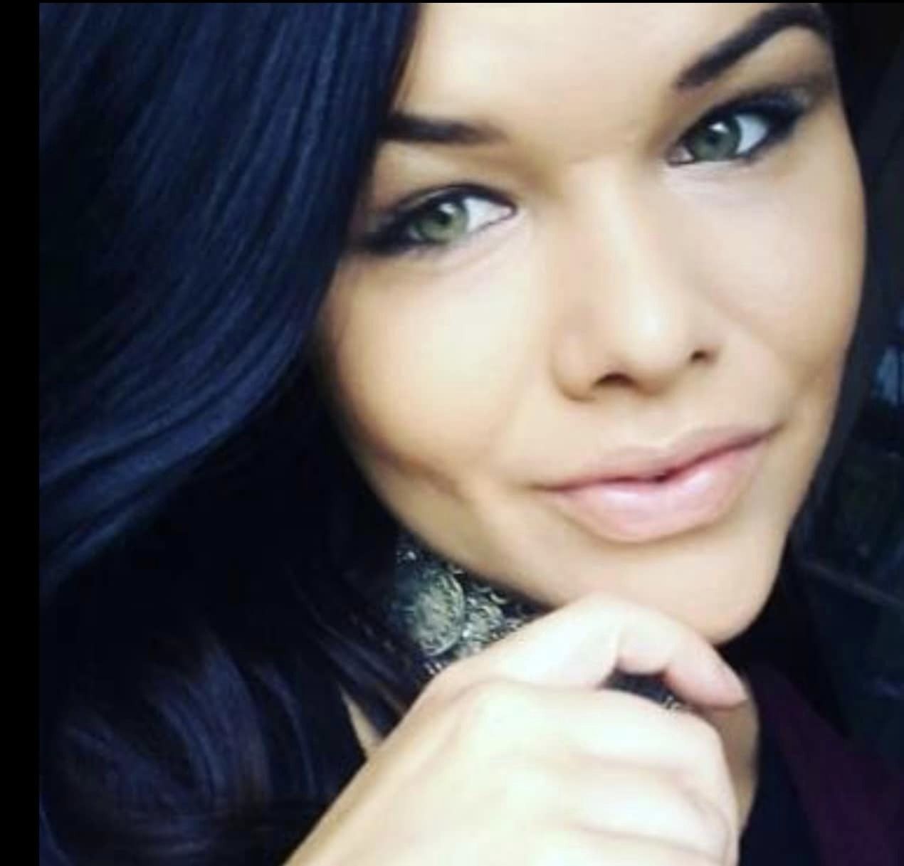 Close up of woman with dark hair smiling at camera