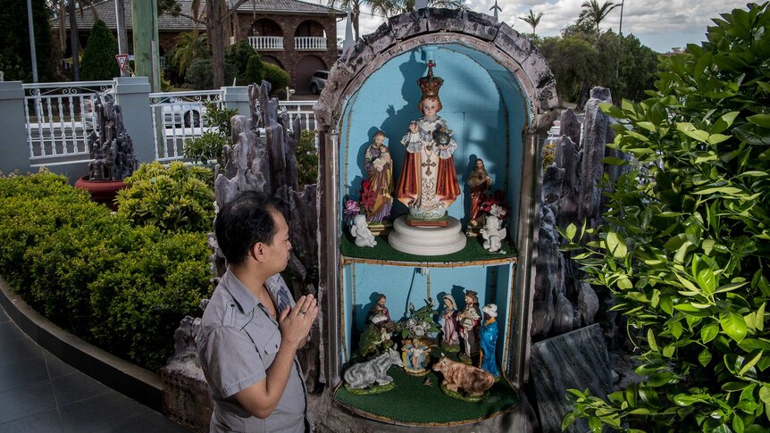 Johnny from Bossley Park in seen praying in his front yard where a religious grotto has been made