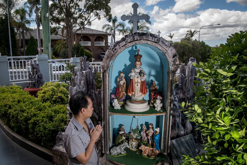 Johnny from Bossley Park in seen praying in his front yard where a religious grotto has been made