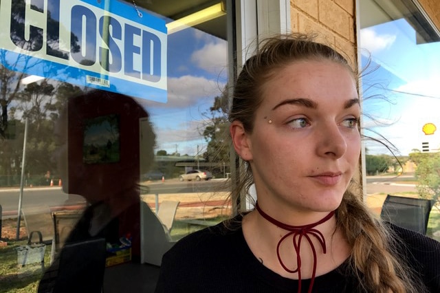 Lily Prosser stands at her cafe door with a closed sign on it.