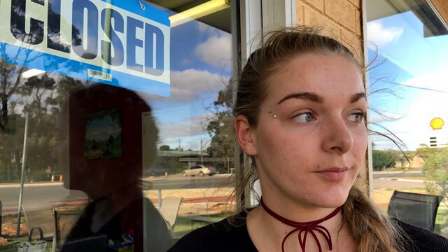 Lily Prosser stands at her cafe door with a closed sign on it.