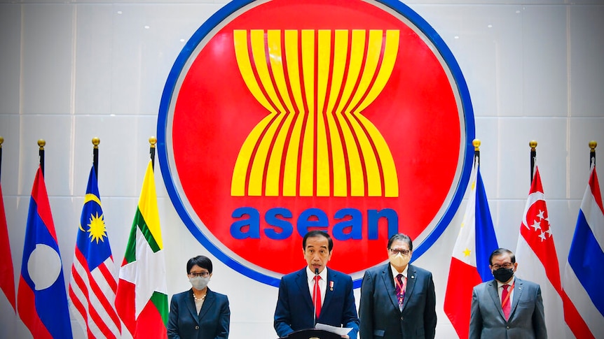 Joko Widodo stands alongside other officials in front of South-East Asian country flags and a large ASEAN logo.