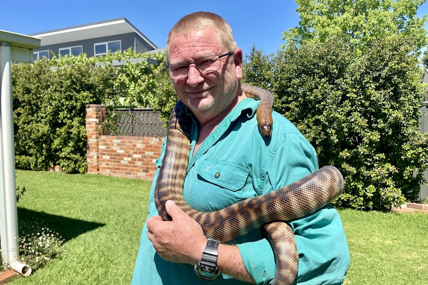 A man with a python wrapped around his neck
