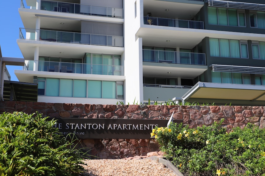A cropped picture of an apartment building, the the garden and a sign displaying Stanton Apartments