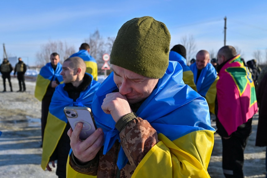 A man wearing a Ukrainian flag speaking on mobile phone. 