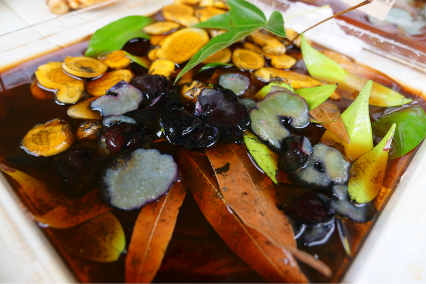 colourful roots, slices of plum and leaves soak in rusty-coloured water