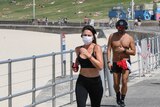 A woman in a face mask jogs along the boardwalk at Bondi Beach.