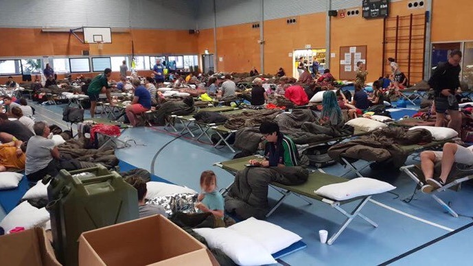 People take shelters at evacuation centre set up at a sports hall in flooded Townsville.