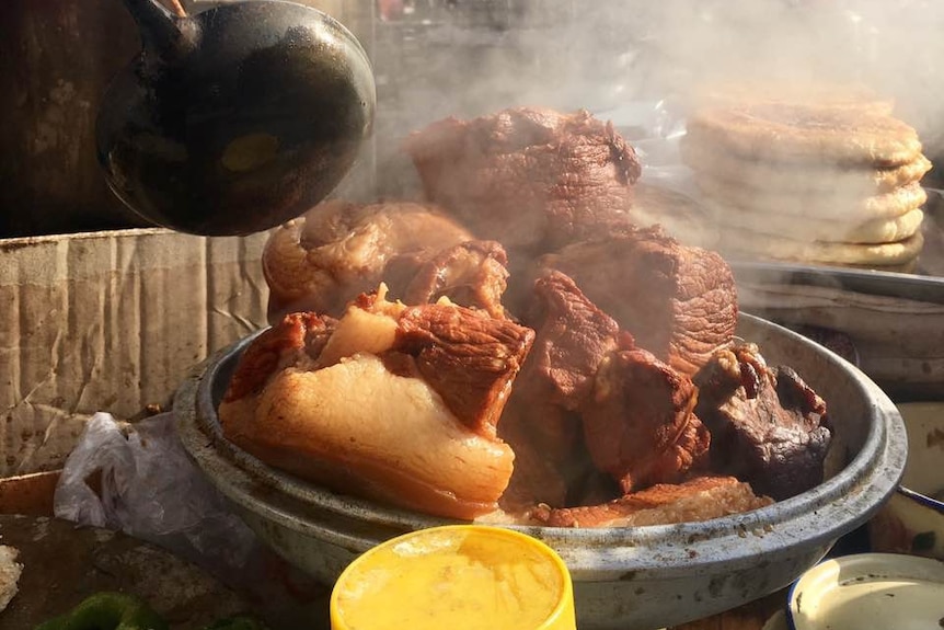 Meat cooks at a market in Zhidan, Shaanxi province, China