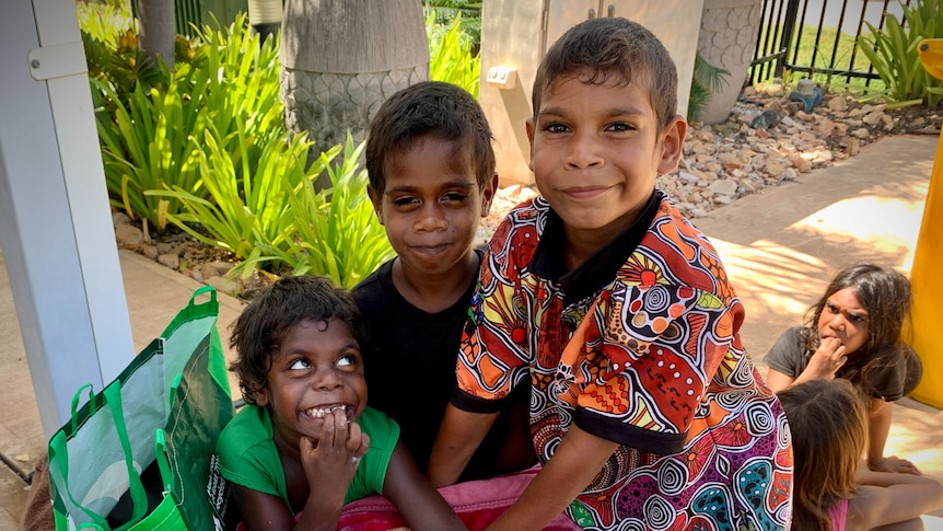 A group of kids gather together outside a garden