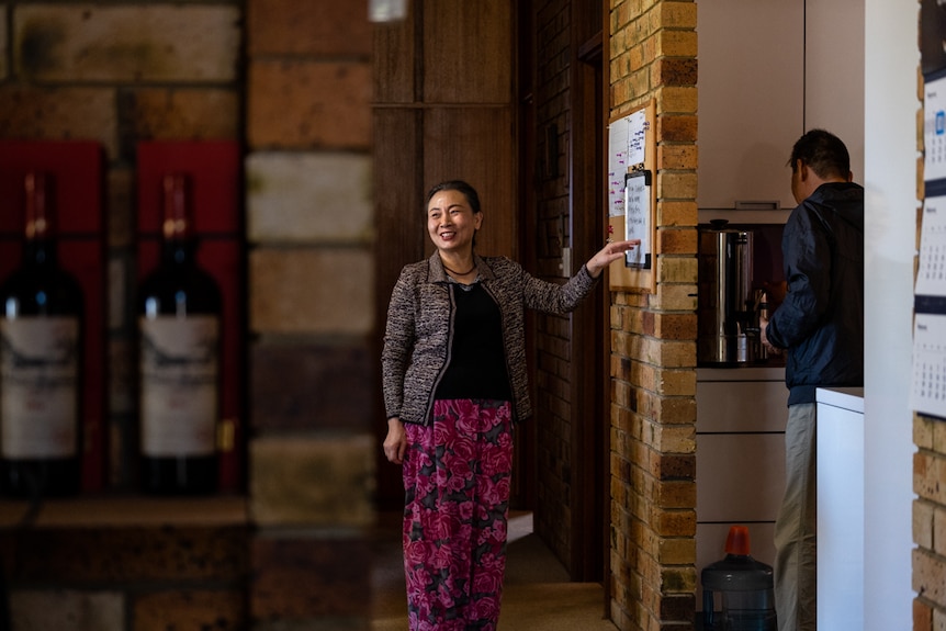 Yingchun Wang looks at the board for upcoming bed and breakfast bookings while her husband makes a cup of the in the background.