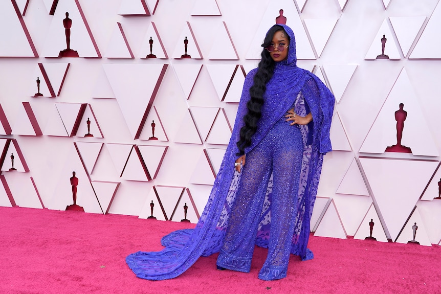 H.E.R. in blue lace cape and jumpsuit.