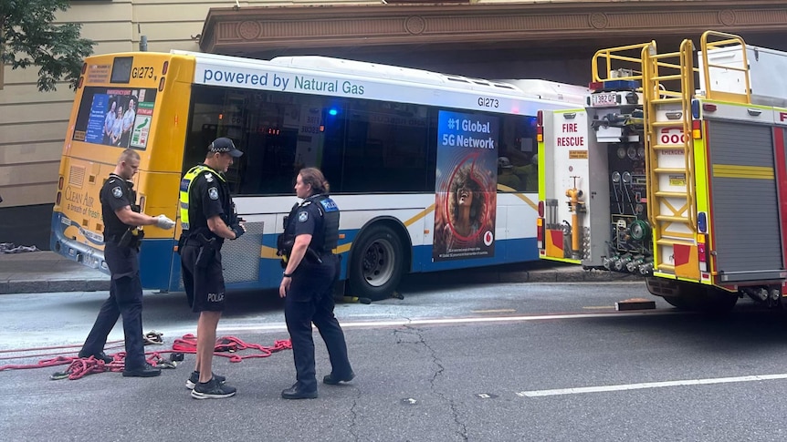 A fire truck is parked near a bus that has mounted the sidewalk.