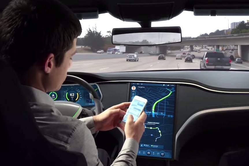 A driver uses his mobile phone while in a driverless car on a multi-lane freeway.