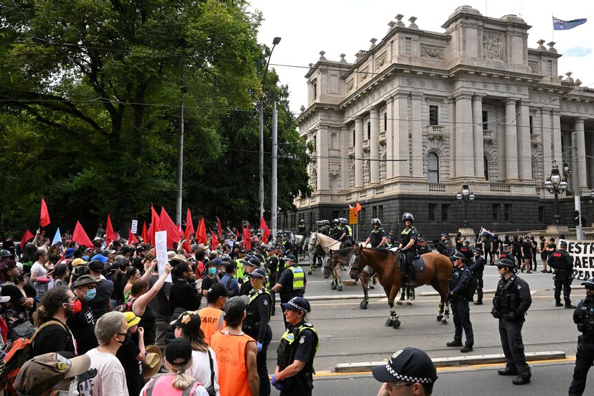 A line of police separates a counter-rally from an anti-trans rally outside Victoria's Parliament House.